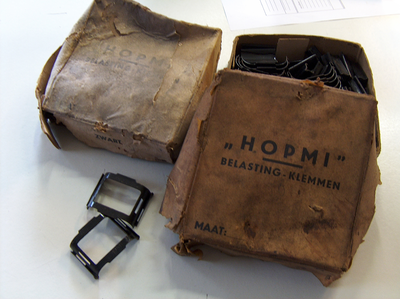 878201 Afbeelding van een doosje met 'belastingklemmen', vervaardigd bij de Hollandsche Patent Metaal Industrie (HOPMI, ...